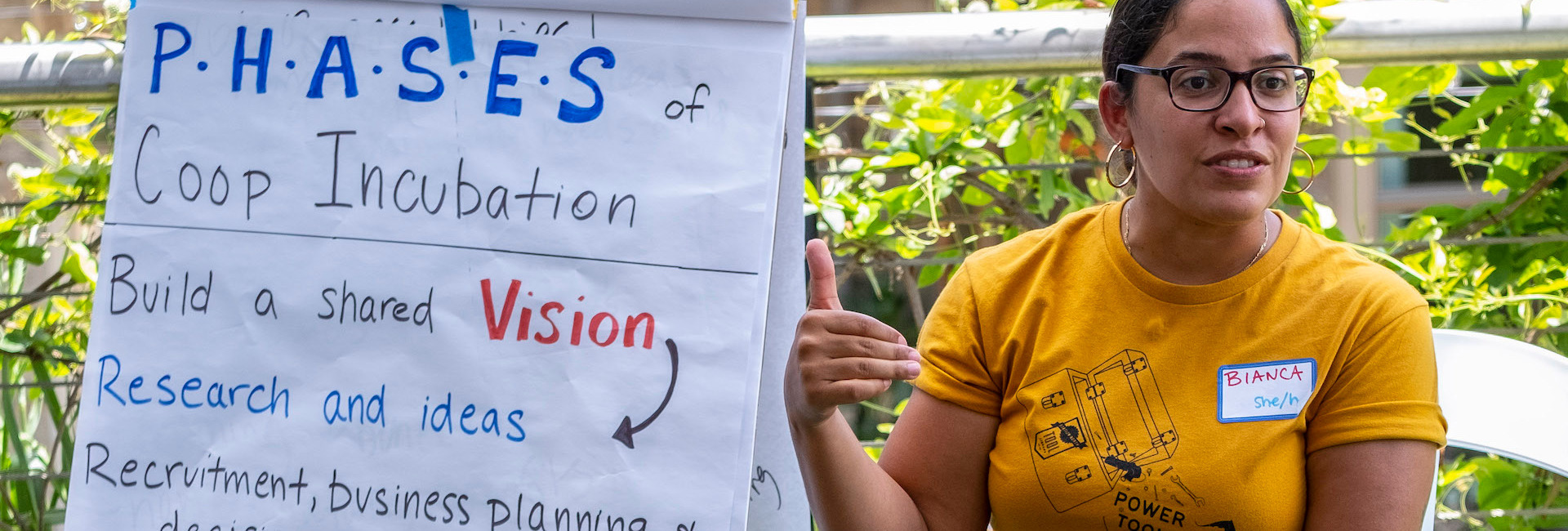 A person sits next to a chart, and appears to be mid sentence. The chart reads some information about co-op incubation.