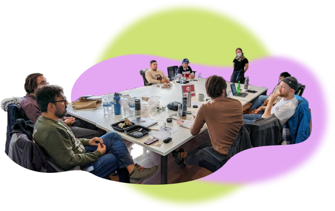 An image of a number of people around a table, engaged in a casual meeting.